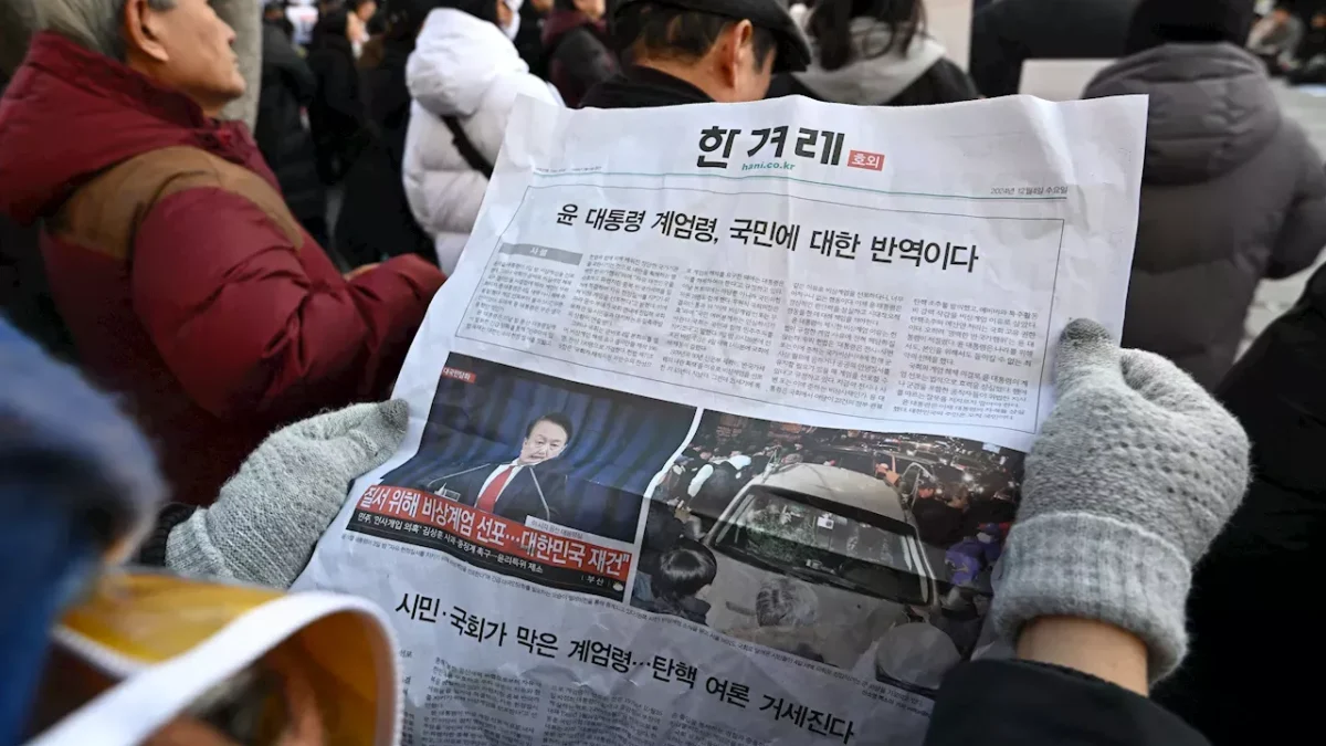 Seorang pria membaca koran edisi tambahan yang dipajang di gerbang kereta bawah tanah di pusat kota Seoul, Kor