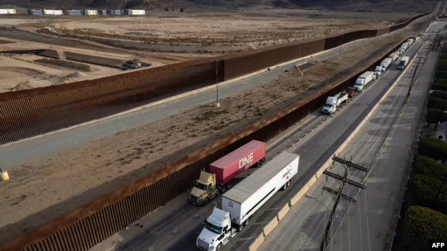 Truk mengantre di dekat tembok perbatasan sebelum menyeberang ke AS di pelabuhan komersial Otay di Tijuana, ne