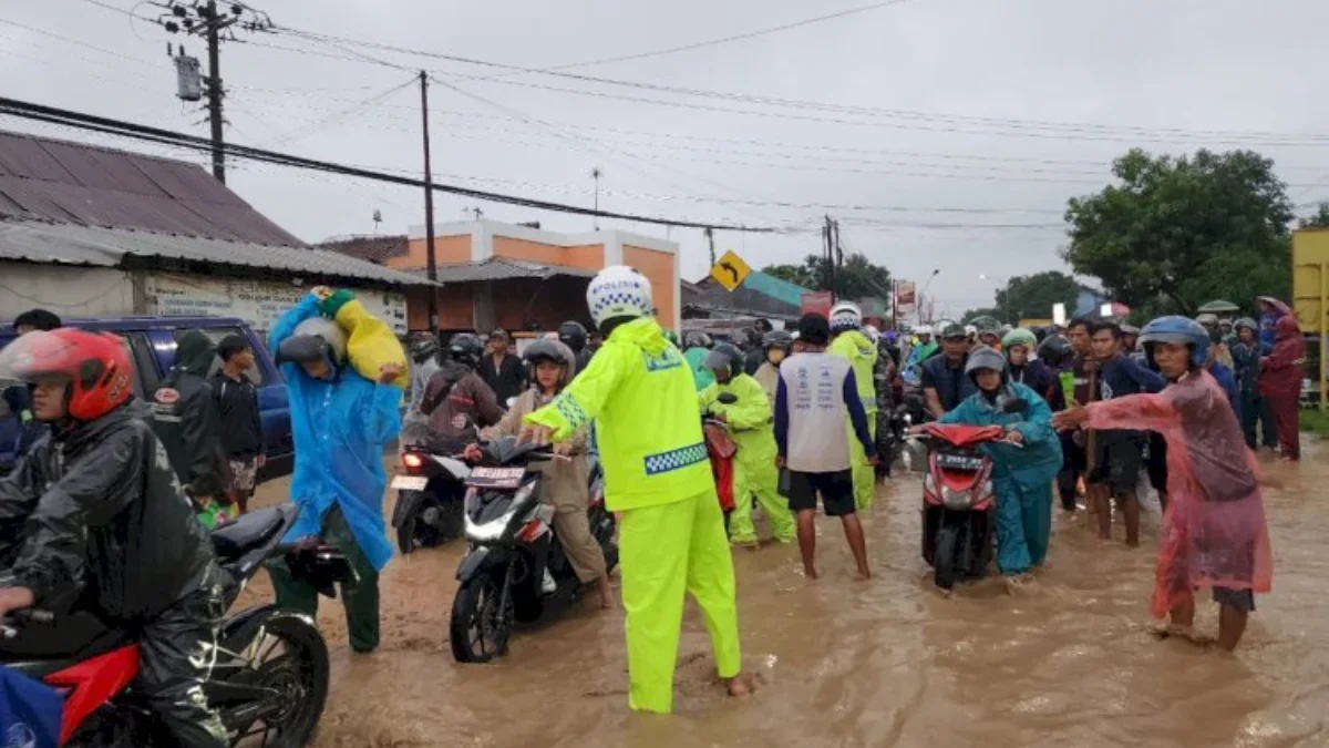 Petugas mengatur arus lalu litas ditengah banjir yang membuat jalan utama Slawi ke Bumiayu lumpuh pada arus mu