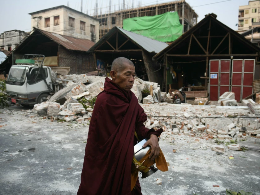 Seorang biksu berjalan melewati rumah-rumah yang rusak di Mandalay pada tanggal 30 Maret 2025. (Sai Aung Main