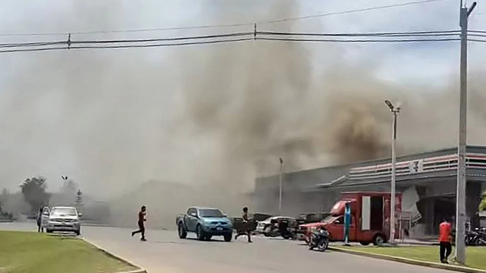 Asap mengepul dari atap sebuah toko swalayan yang terhubung dengan sebuah SPBU di Provinsi Sisaket setelah ter