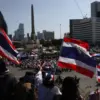 Para demonstran mengibarkan bendera Thailand saat mereka bergabung dalam rapat umum di Monumen Kemenangan di B