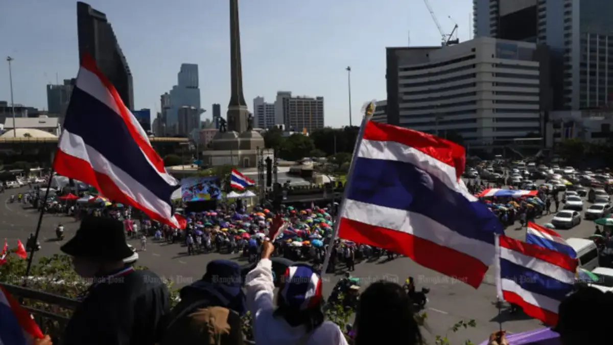 Para demonstran mengibarkan bendera Thailand saat mereka bergabung dalam rapat umum di Monumen Kemenangan di B