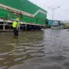 Petugas tengah mengatur kendaraan di ruas jalan yang masih tergenang air. (Ist)