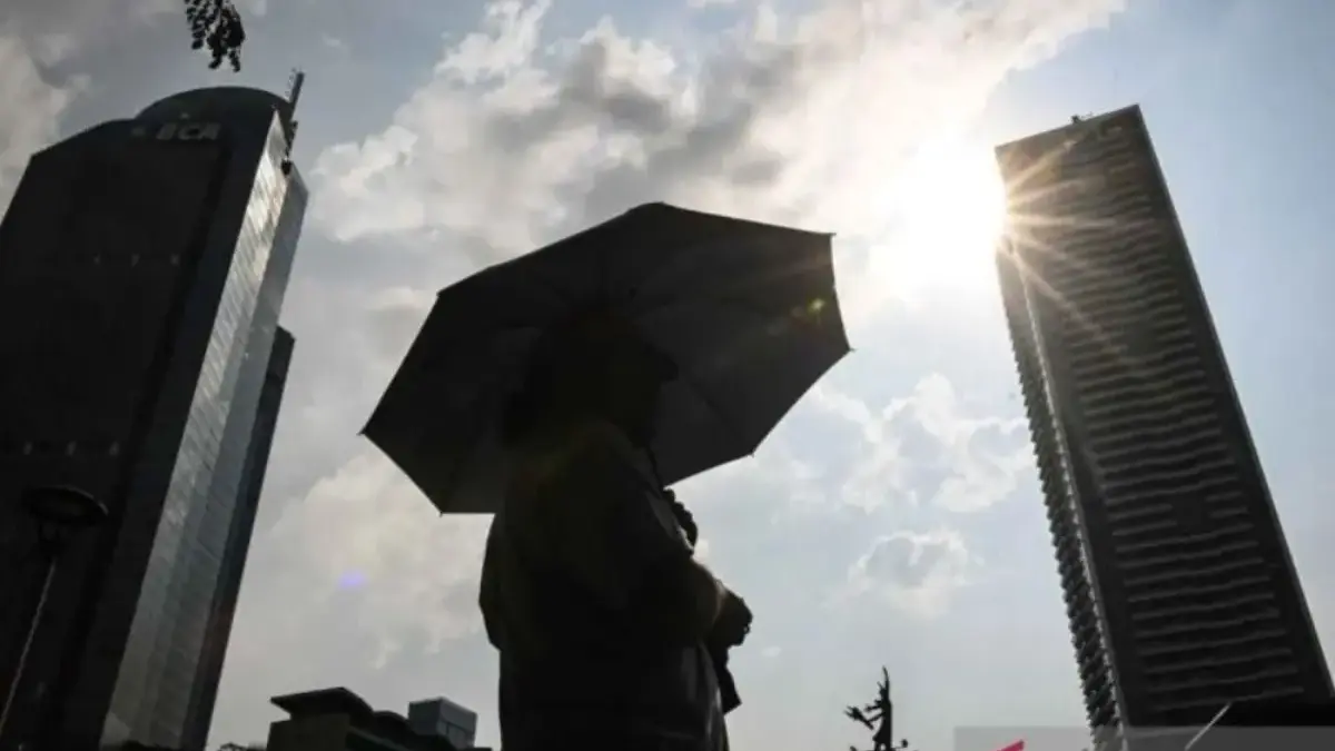 Warga menggunakan payung saat cuaca terik di kawasan Bundaran HI, Jakarta, Rabu (15/10/2025). Badan Meteorolog