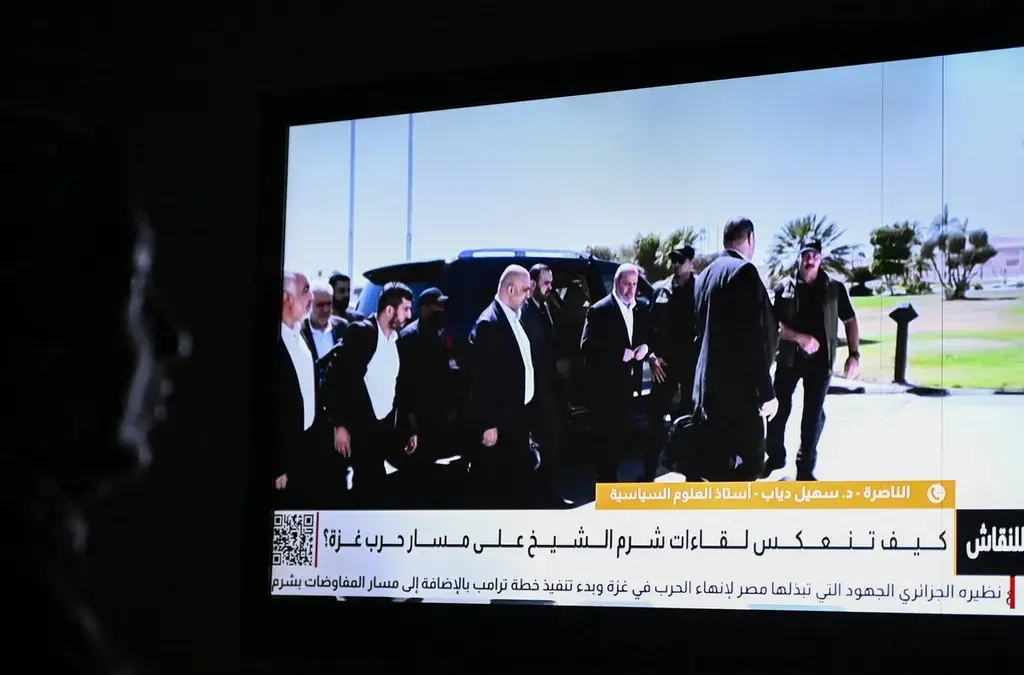 Hamas-Israel Sepakat Rencana Fase Pertama Akhiri Perang di Jalur Gaza Seorang perempuan Mesir menonton berita di saluran lokal yang menampilkan gambar negosiator utama Hamas, Khali