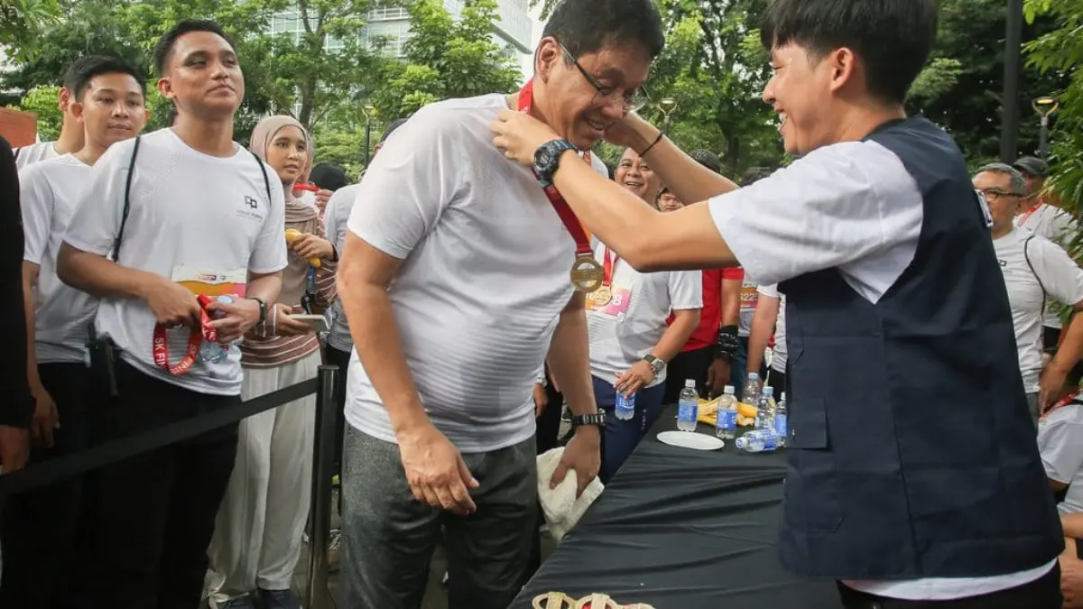 Menteri Keuangan Purbaya Yudhi Sadewa (tengah) mendapatkan medali usai berlari mencapai garis finish saat meng