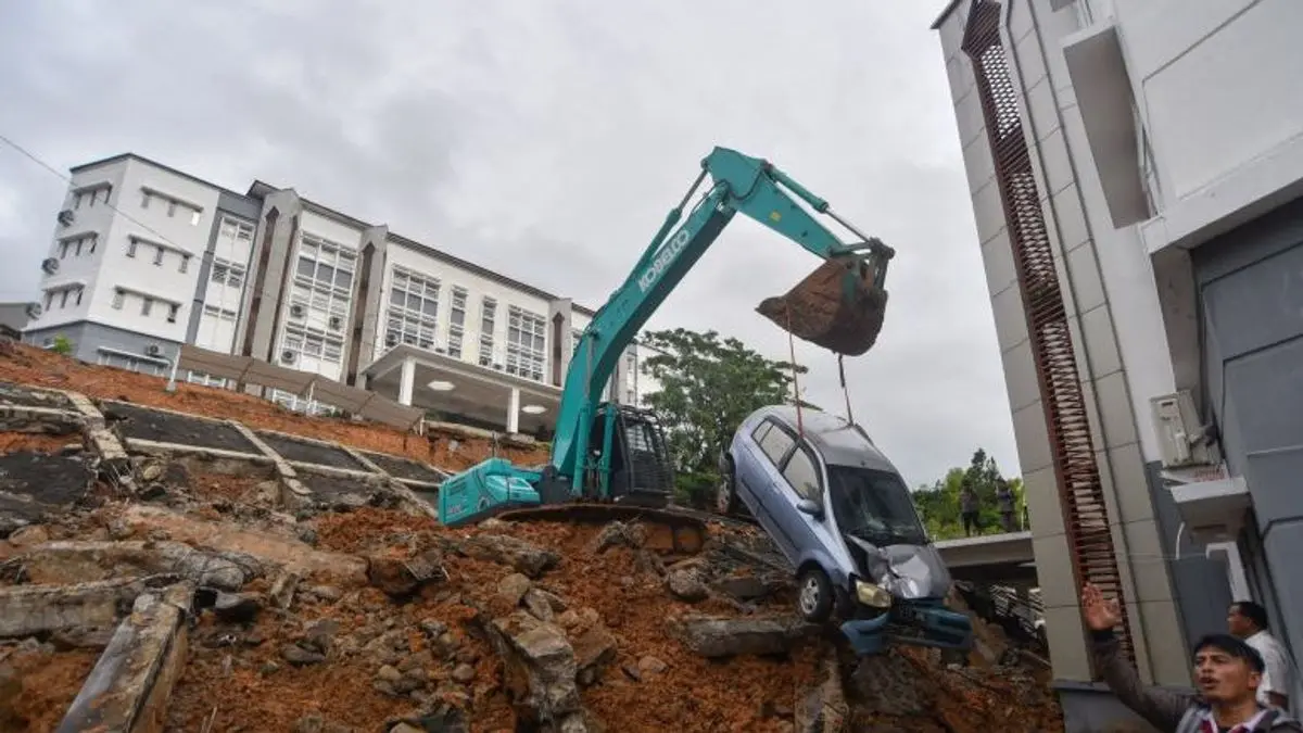 Operator mengoperasikan alat berat mengangkat mobil yang terdampak longsor di kampus UIN Imam Bonjol Sungai Ba