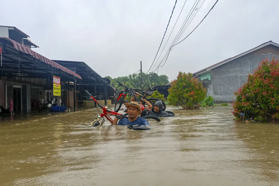 Warga membawa barang-barang ke tempat yang aman setelah hujan lebat membanjiri lingkungan di Kecamatan Medankr
