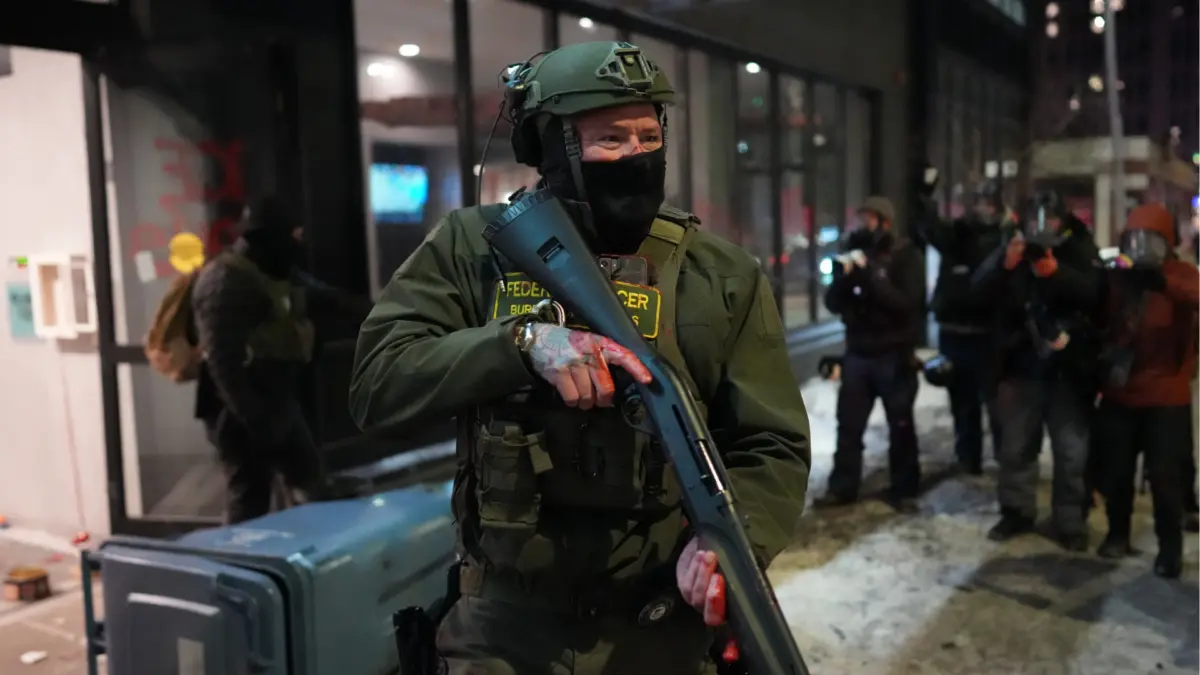 Pakar Ingatkan Amerika Serikat, Pengerahan Besar-besaran Aparat Federal Berisiko Picu Eskalasi Perang Saudara Seorang agen federal berjaga di dekat sebuah hotel selama protes demonstrasi sebagai tanggapan atas operasi pe
