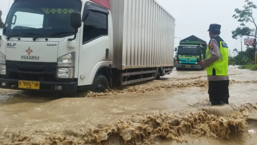 Anggota Polsek Genuk saat sedang mengatur lalu lintas di Jalan Pantura Demak-Semarang yang tergenang banjir.