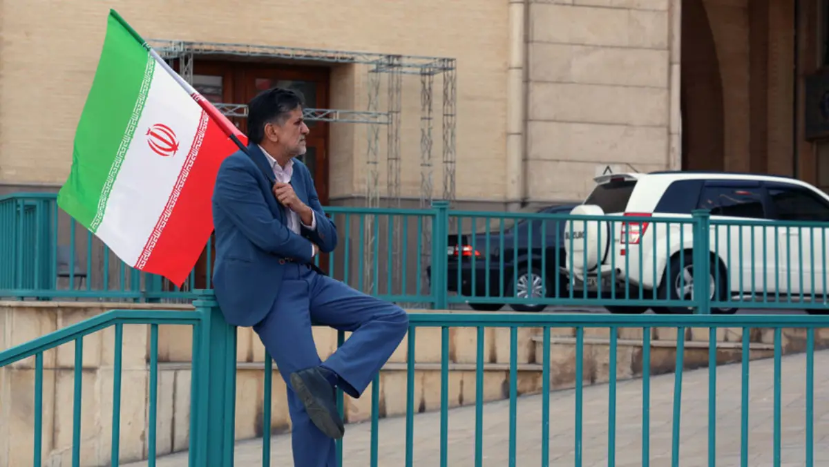 Seorang pria Iran memegang bendera nasional Iran selama upacara peringatan bagi mereka yang tewas dalam protes