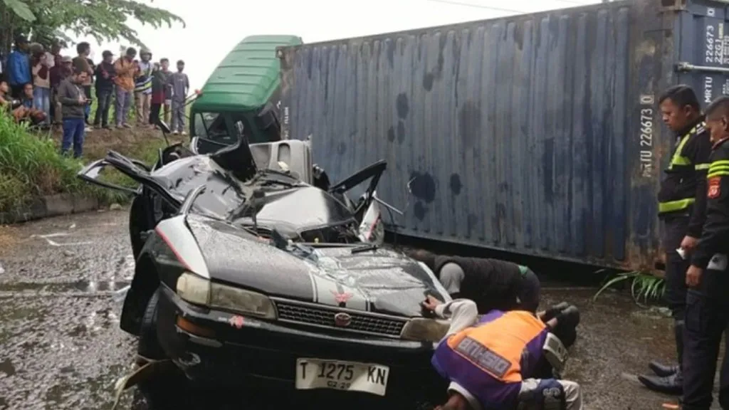 Petugas saat evakuasi mobil sedan dan truk kontainer yang terlibat kecelakaan di Karawang. (Polres Karawang)