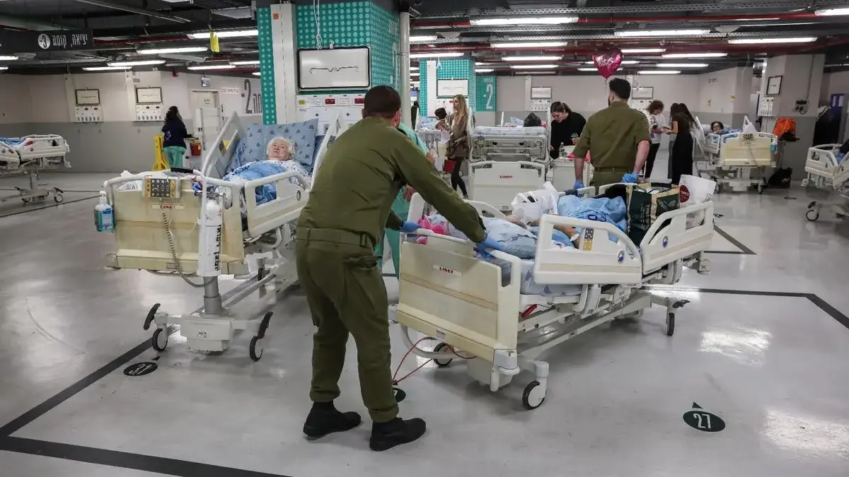 Anggota personel keamanan Israel memindahkan seorang pasien di area parkir Sourasky Medical Center demi kesela