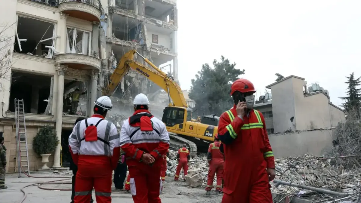 Petugas pemadam kebakaran dengan bantuan ekskavator membersihkan puing-puing dari bangunan yang hancur di Teh