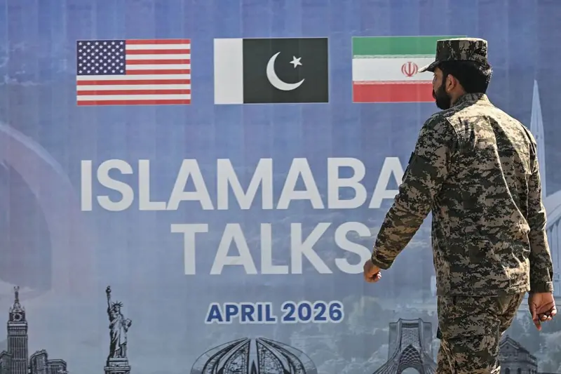 Yaman Ingatkan Eskalasi Militer Meningkat Jika Amerika Serikat-Israel Kembali Serang Iran Seorang anggota militer Pakistan berjalan melewati papan reklame perundingan perdamaian AS-Iran di Islamabad,