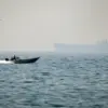 Sebuah perahu motor berlayar di sepanjang pantai di luar kota Al Jeer Selat Hormuz, kapal tanker terlihat di l