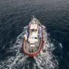 Pemandangan dari udara ini menunjukkan para kru yang mengenakan setelan hazmat di atas perahu yang bergerak me