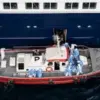 Kapal ambulans membawa anggota kru mengenakan pakaian hazmat saat mendekati pintu pilot di sisi kanan kapal pe