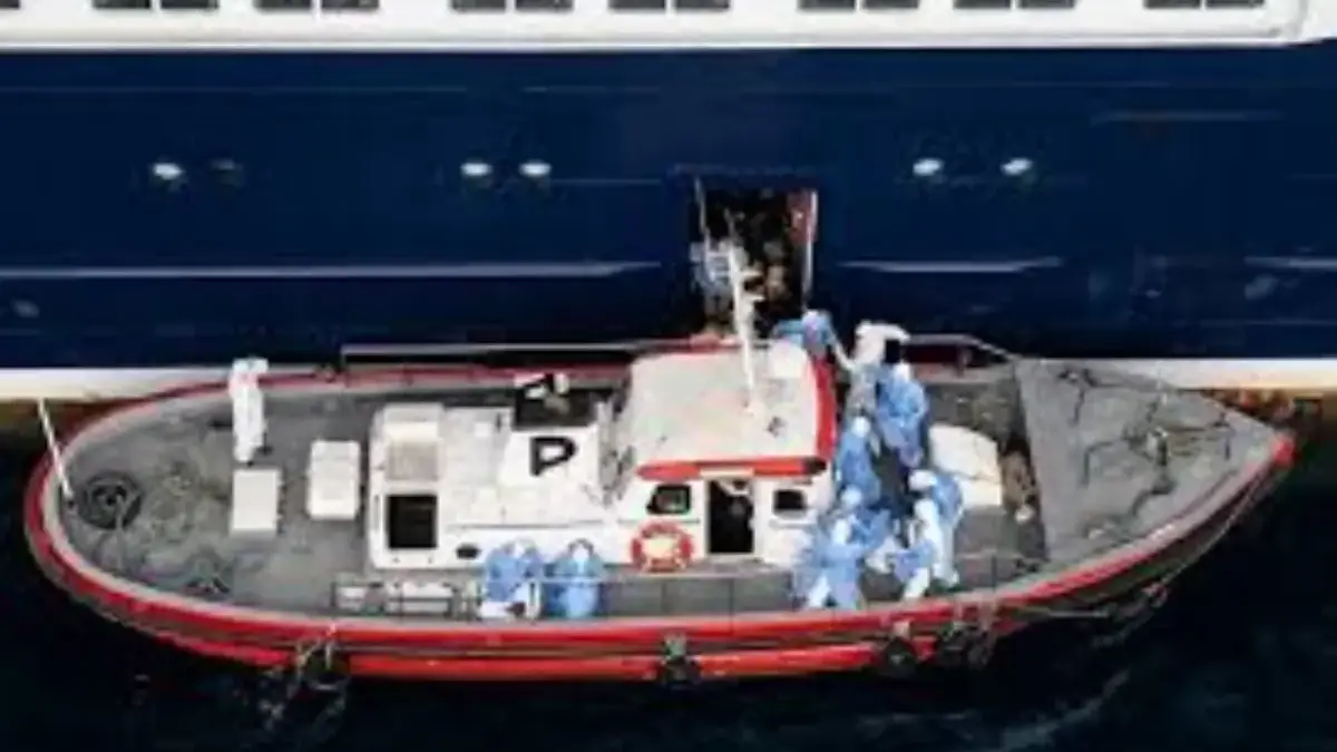 Kapal ambulans membawa anggota kru mengenakan pakaian hazmat saat mendekati pintu pilot di sisi kanan kapal pe
