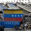 Bendera Venezuela di dinding yang rusak di tengah reruntuhan bangunan yang runtuh setelah gempa bumi di Caraba