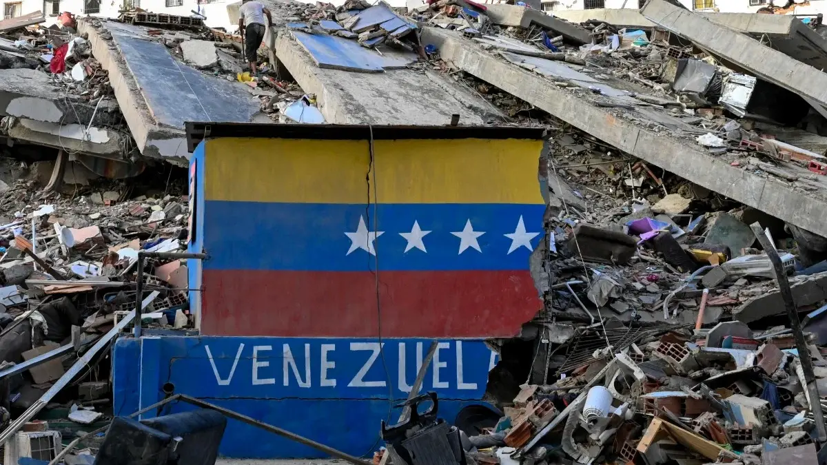 Bendera Venezuela di dinding yang rusak di tengah reruntuhan bangunan yang runtuh setelah gempa bumi di Caraba