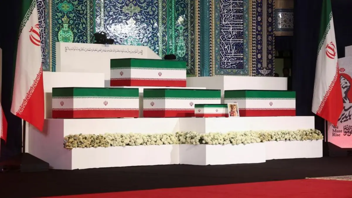 Pemuka agama Iran bersama para pelayat memberikan penghormatan di hadapan peti jenazah Ali Khamenei serta angg