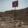 Sebuah tanda peringatan ranjau darat berdiri di ladang ranjau yang membentang setidaknya enam kilometer di sep