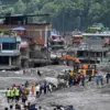 Para pekerja menggunakan ekskavator untuk membersihkan lumpur pascabanjir bandang di Dhunge Bazaar, Distrik Nu