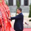 Presiden Tiongkok Xi Jinping merapikan pita pada keranjang bunga saat upacara pemberian karangan bunga kepada